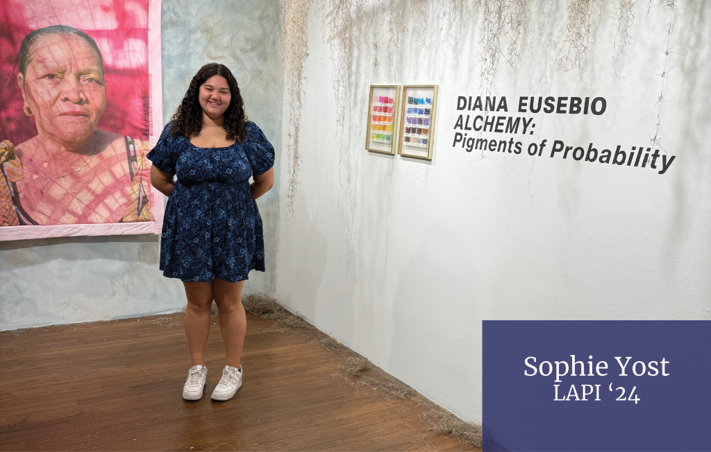 Sophia Yost stands in front of an art exhibit. The Bottom right corner reads "Sophia Yost, LAPI '24"