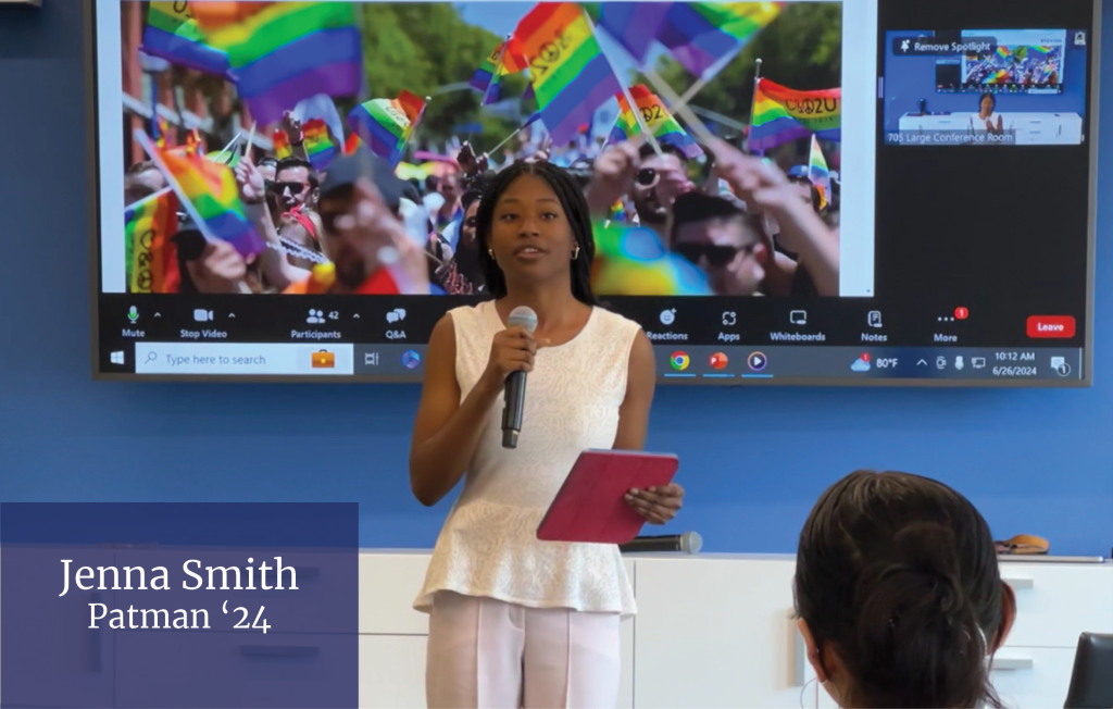 A young woman stands in from of a presentation screen while speaking into a microphone and holding a tablet. Bottom left corner reads "Jenna Smith, Patman '24"