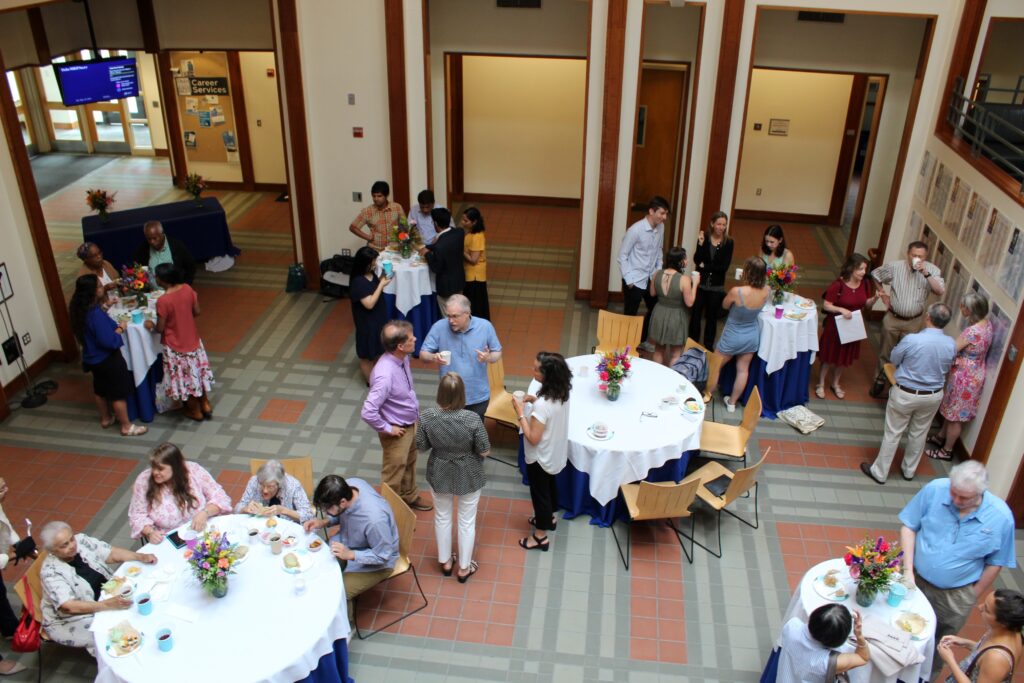 Image from above of 2023 HLP graduation event: people mingle at tables with flowers on them